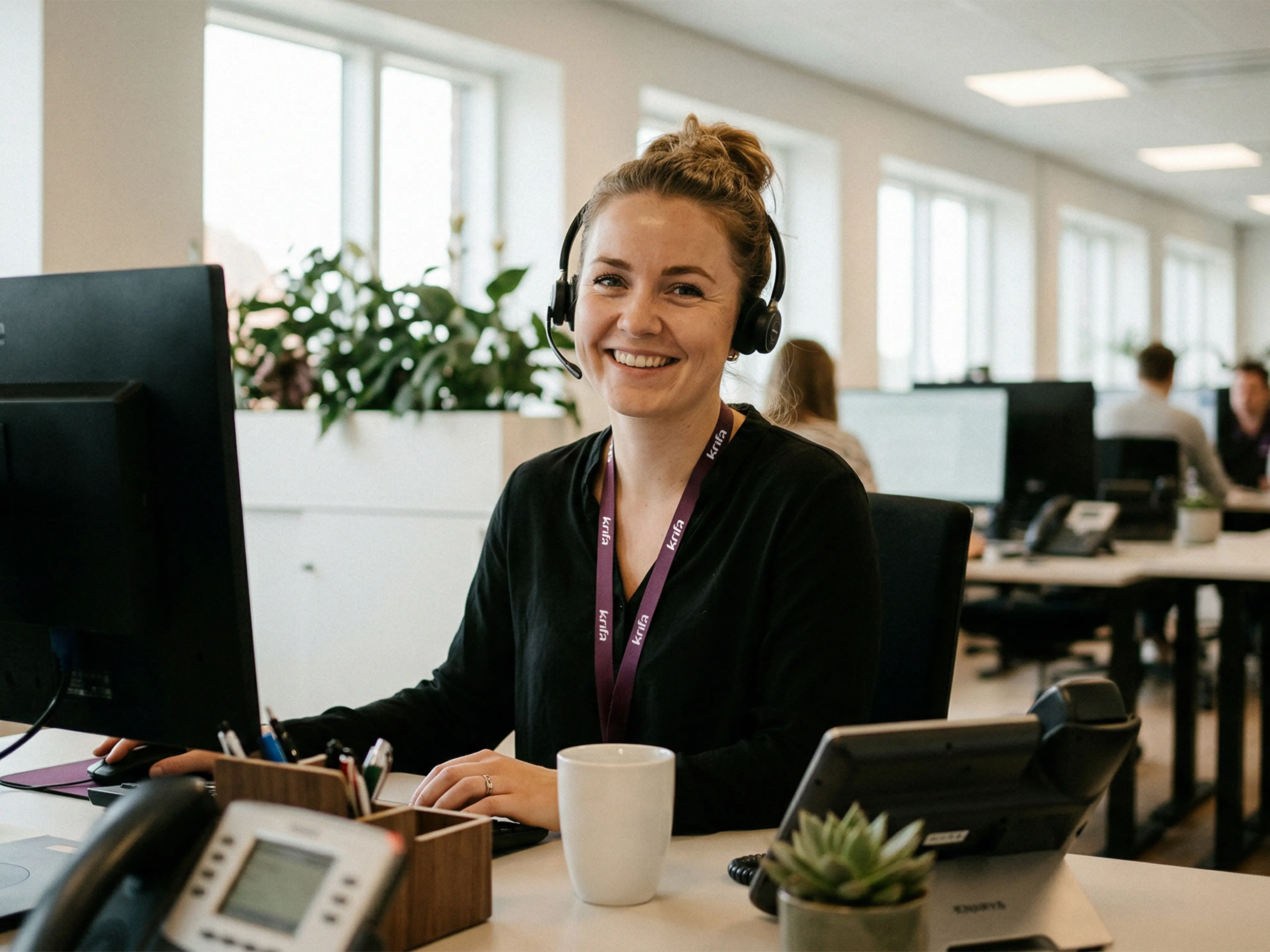 Krifa-medarbejder sidder klar til at besvare dit opkald ved telefonen